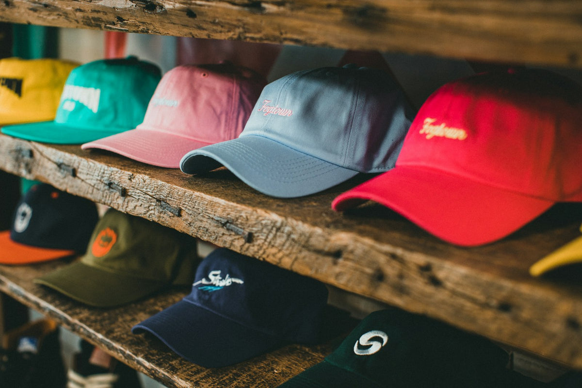 Gorras de distintos estilos y colores en una repisa de madera