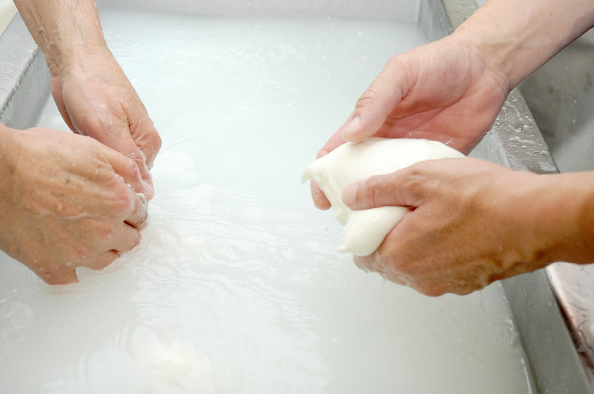 Manos lavando una prenda a mano con agua y jabón